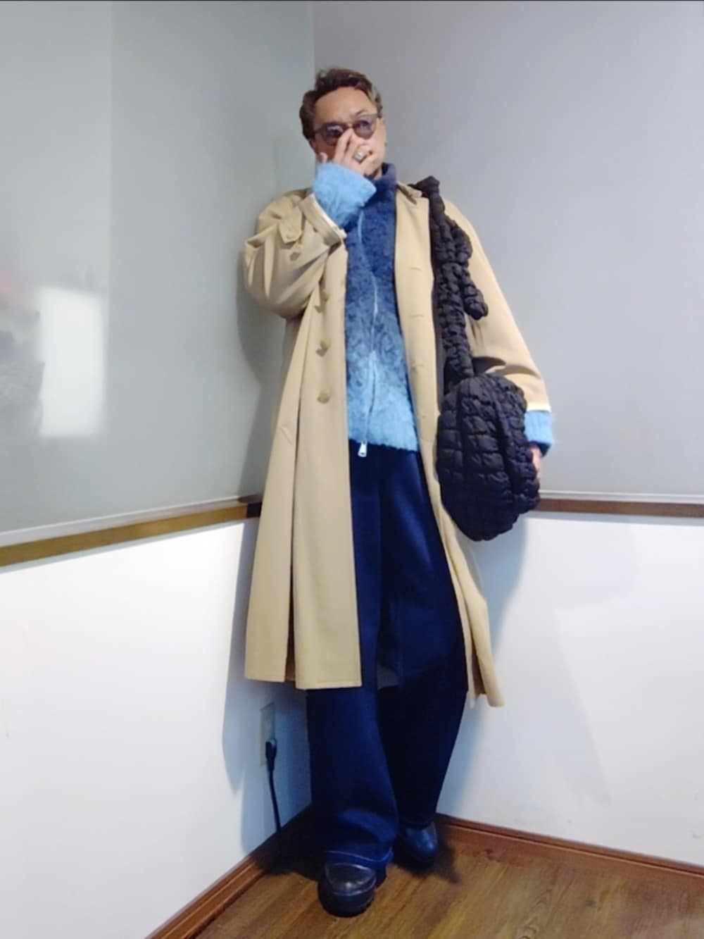 ブルー系のニット/セーター、ピンク系のTシャツ/カットソー、ベージュ系のトレンチコートを着用したメンズの秋コーディネートの3枚目の写真