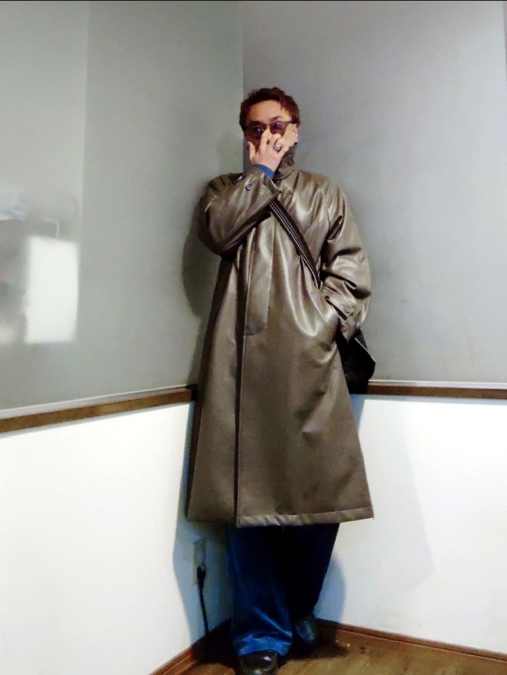 グリーン系のステンカラーコート、ブルー系のブルゾン、ブルー系のショルダーバッグを着用したメンズの春コーディネートの2枚目の写真