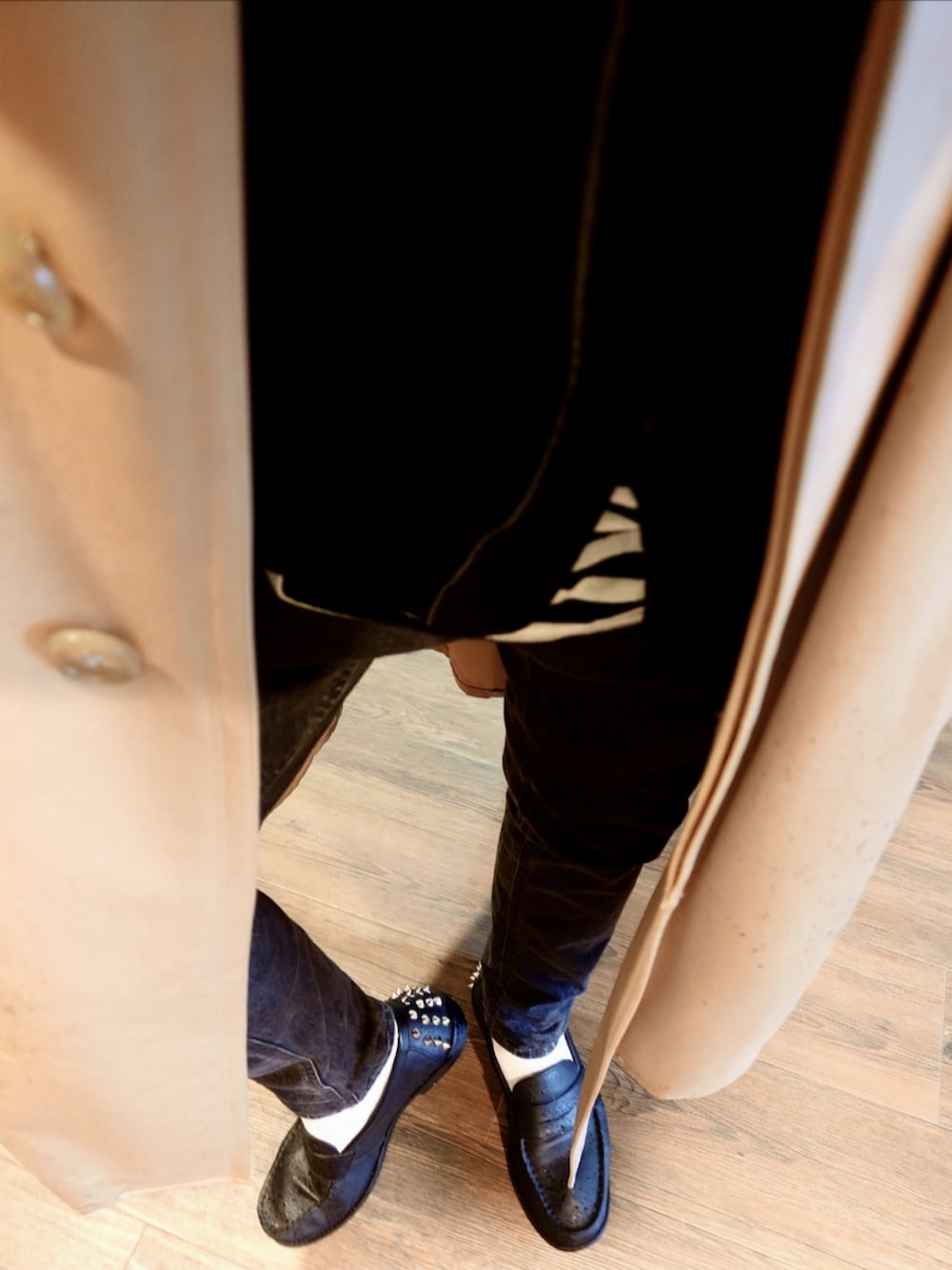 ベージュ系のトレンチコート、ブラック系のカーディガン/ボレロ、ホワイト系のショルダーバッグを着用したメンズの秋コーディネートの2枚目の写真