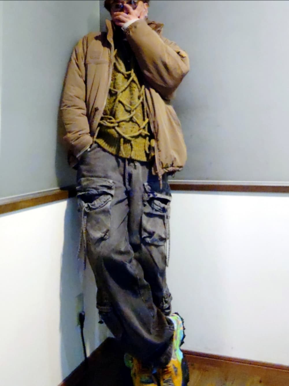 グリーン系のニット/セーター、ベージュ系のダウンジャケット/コート、ブラック系のカーゴパンツを着用したメンズの冬コーディネートの2枚目の写真