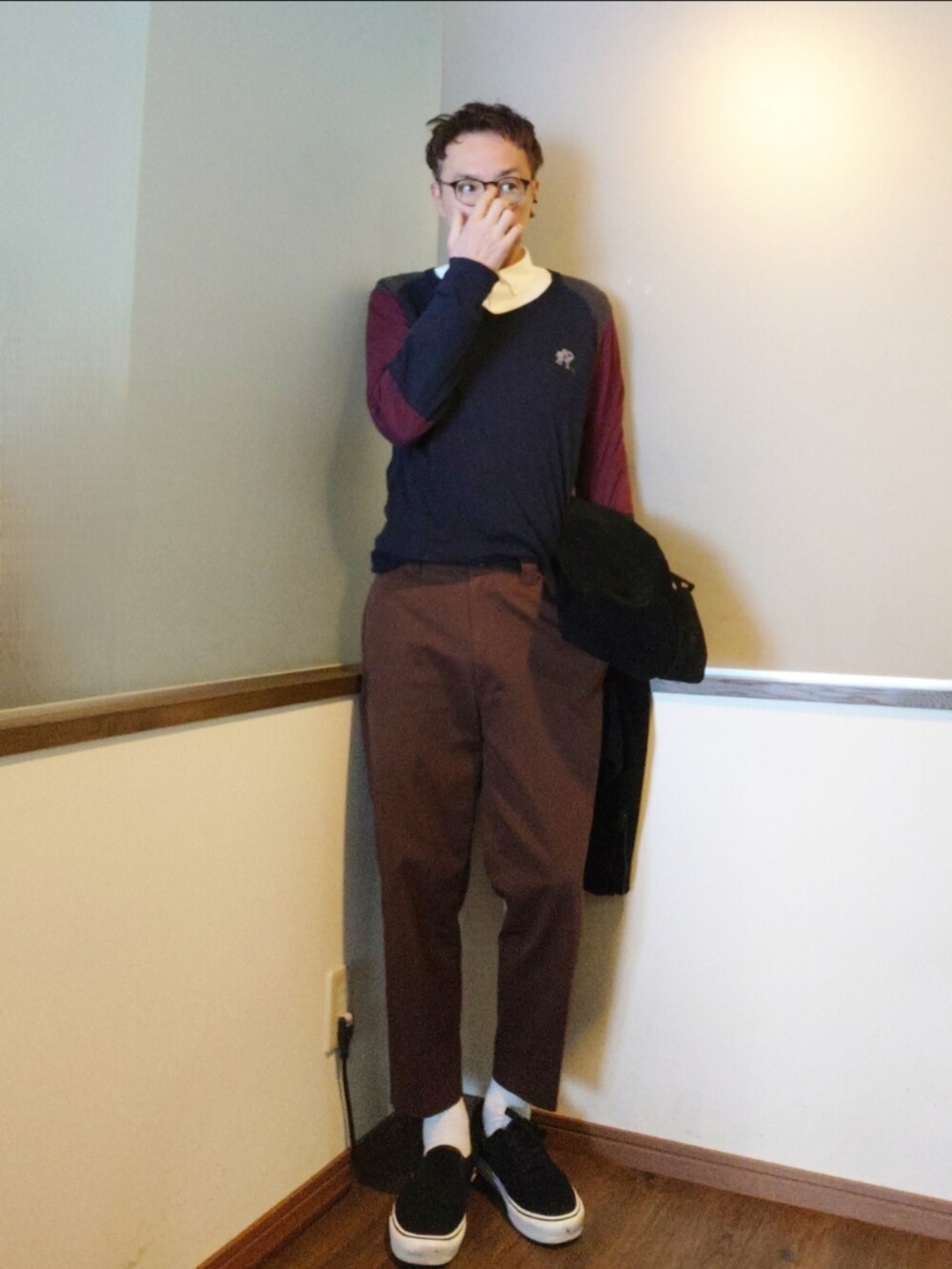 ブラック系のライダースジャケット、ブルー系のニット/セーター、ブラウン系のチノパンツを着用したメンズの春コーディネートの2枚目の写真