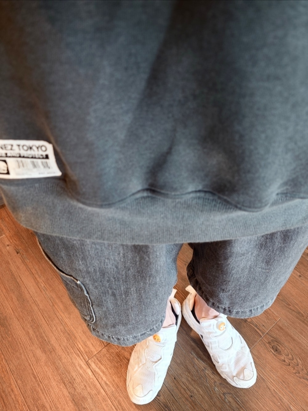 グレー系のパーカー、ホワイト系のスニーカー、ブラック系のデニムパンツを着用したメンズの夏コーディネートの3枚目の写真