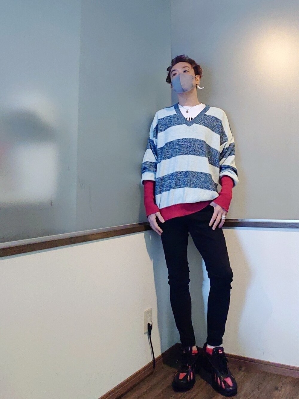 ブルー系のニット/セーター、ブラック系のデニムパンツ、ブラック系のスニーカーを着用したメンズの春コーディネートの2枚目の写真