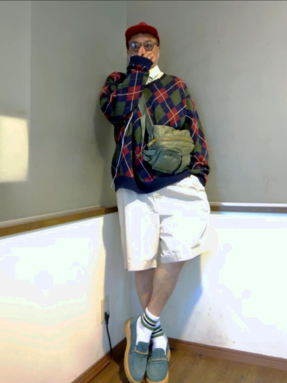 ブルー系のニット/セーター、ベージュ系のチノパンツ、グリーン系のボディバッグ/ウエストポーチを着用したメンズの秋コーディネートの2枚目の写真