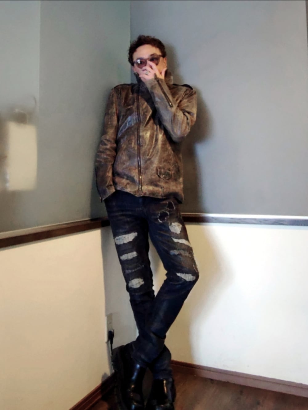 ブラック系のデニムパンツ、ブラック系のブーツ、ブラウン系のライダースジャケットを着用したメンズの春コーディネートの2枚目の写真