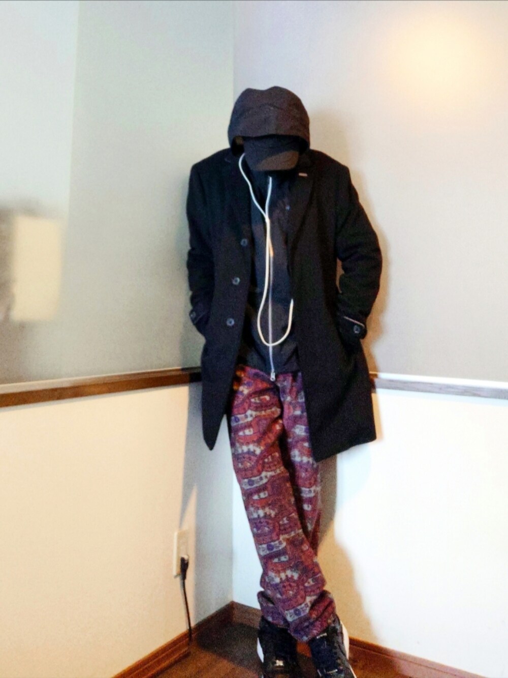 ブラック系のチェスターコート、ブラック系のナイロンジャケット、レッド系のパンツを着用したメンズの冬コーディネートの3枚目の写真