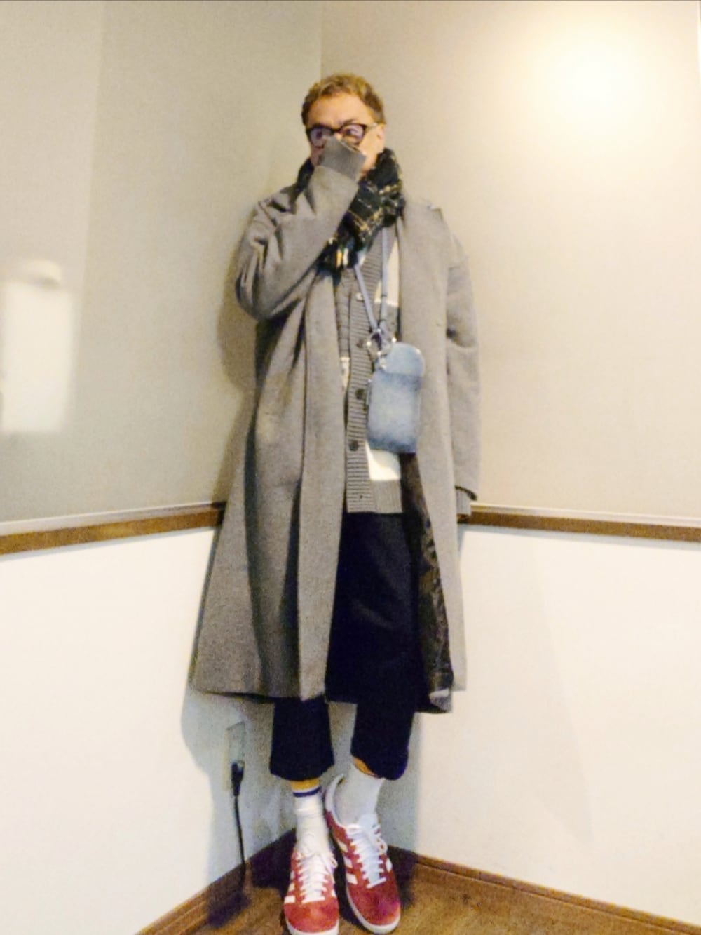 グレー系のチェスターコート、グレー系のカーディガン/ボレロ、ブルー系のチノパンツを着用したメンズの秋コーディネートの2枚目の写真