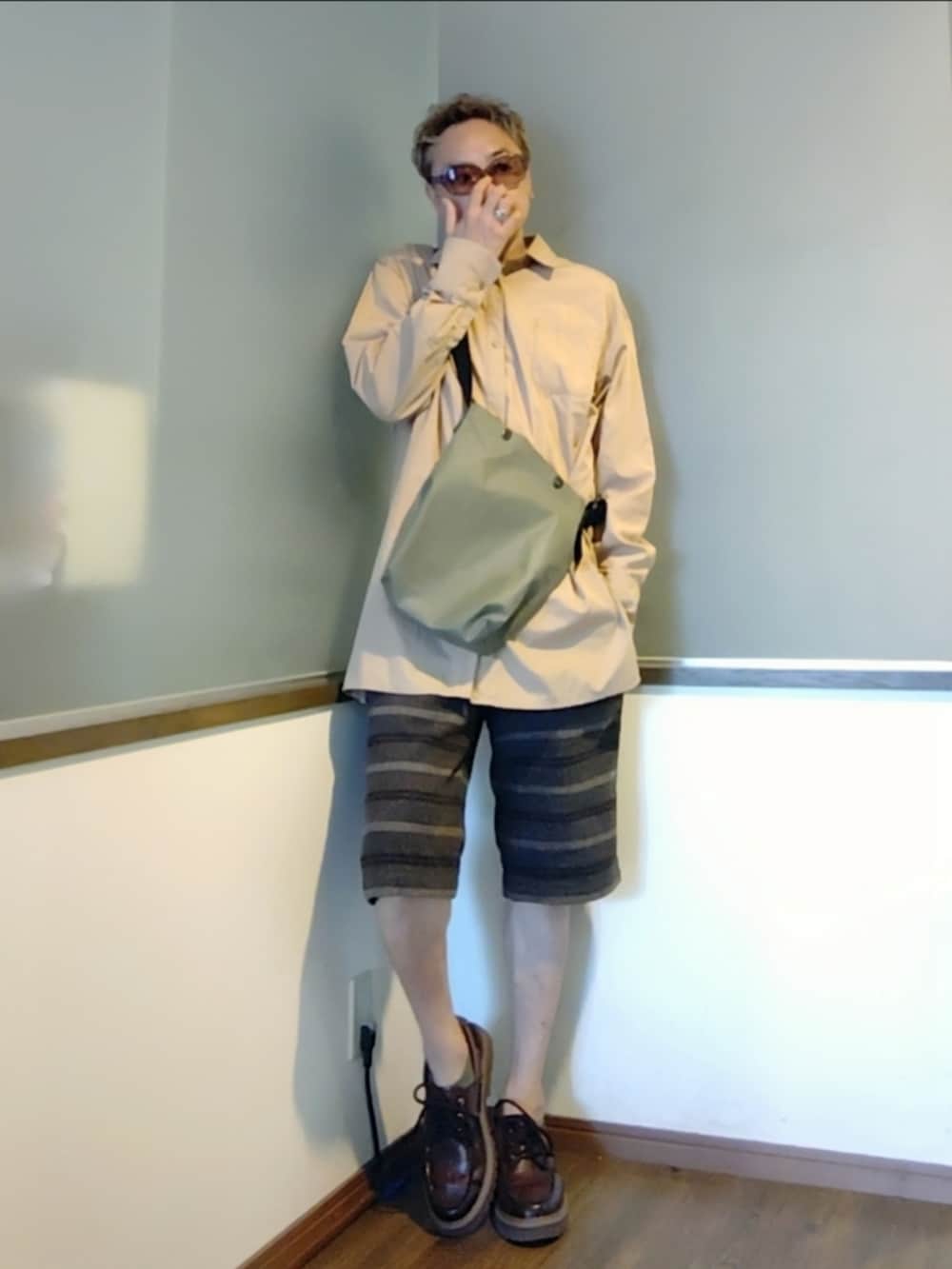 ブラウン系のその他パンツ、ブラウン系のモカシン/デッキシューズ、グリーン系のショルダーバッグを着用したメンズの秋コーディネートの2枚目の写真