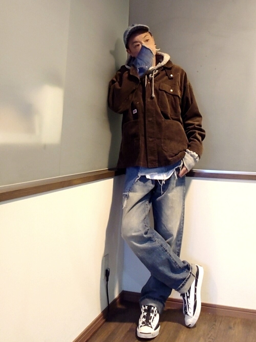 ブラウン系のカバーオール、グレー系のパーカー、ブルー系のデニムパンツを着用したメンズの春コーディネートの2枚目の写真