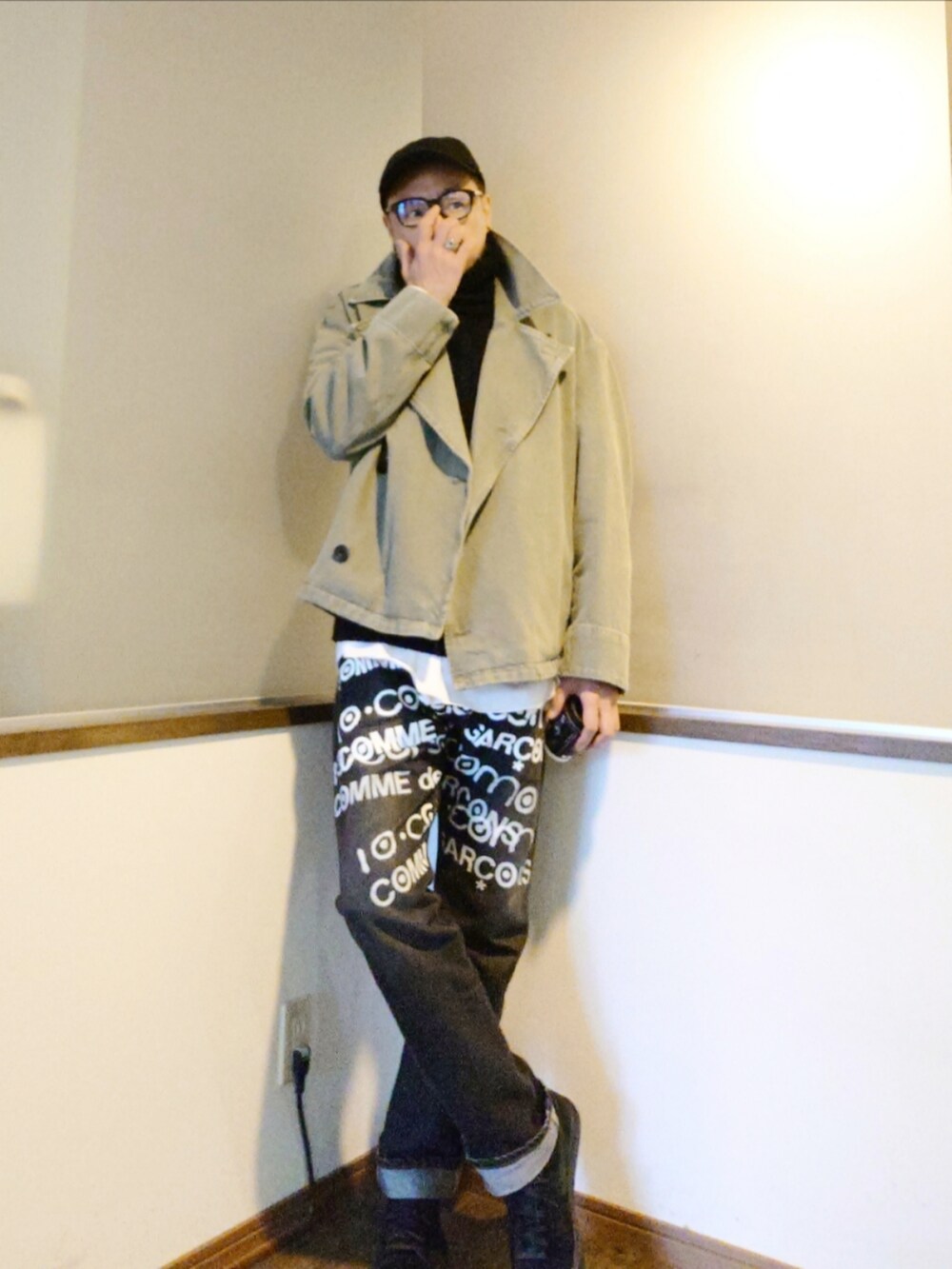 ブラック系のデニムパンツ、ホワイト系のシャツ/ブラウス、グリーン系のトレンチコートを着用したメンズの秋コーディネートの2枚目の写真