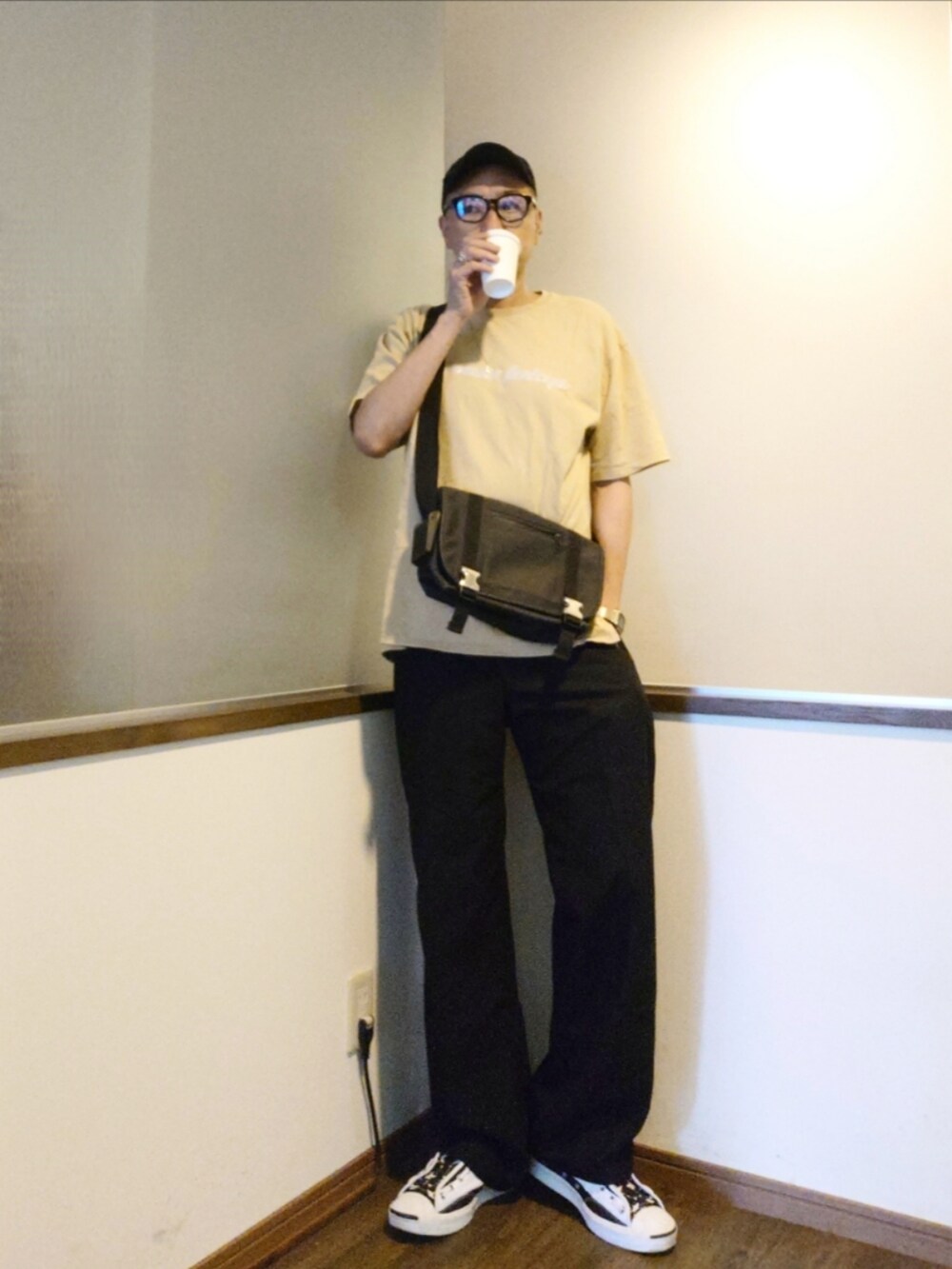 ベージュ系のTシャツ/カットソー、ブラック系のスラックス、ホワイト系のスニーカーを着用したメンズの夏コーディネートの2枚目の写真