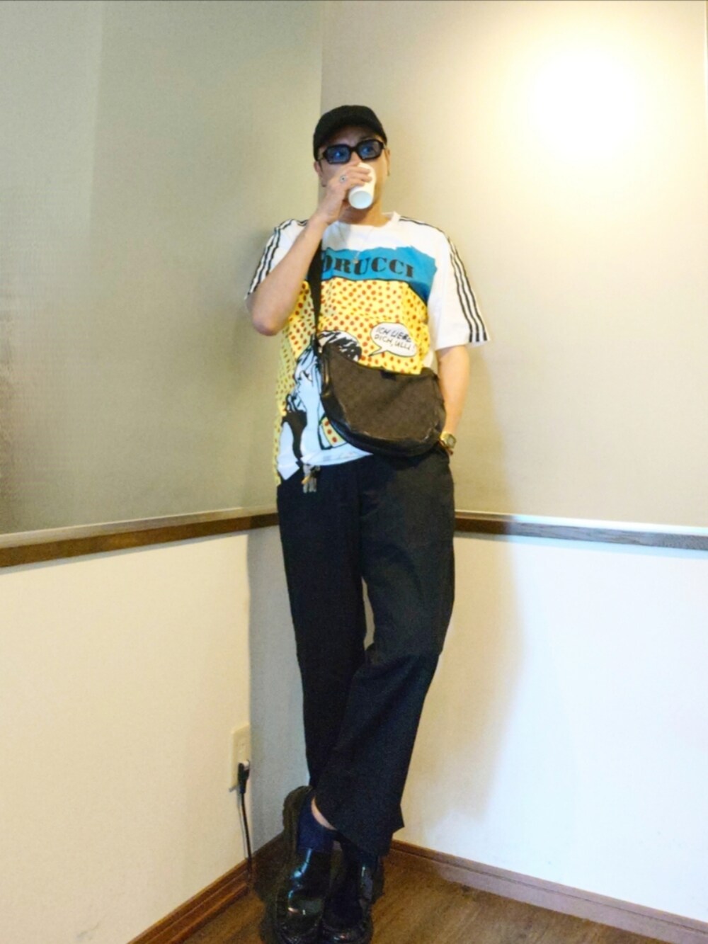 ブラック系のショルダーバッグ、ホワイト系のTシャツ/カットソー、ブラック系のチノパンツを着用したメンズの夏コーディネートの2枚目の写真