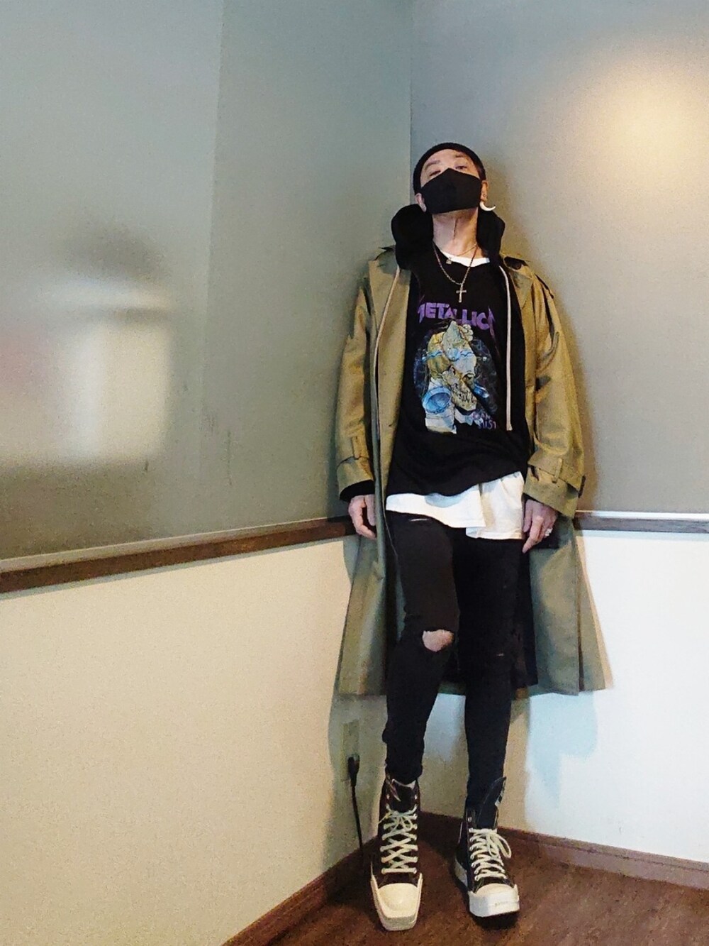 グリーン系のトレンチコート、ブラック系のTシャツ/カットソー、ブラック系のデニムパンツを着用したメンズの春コーディネートの2枚目の写真
