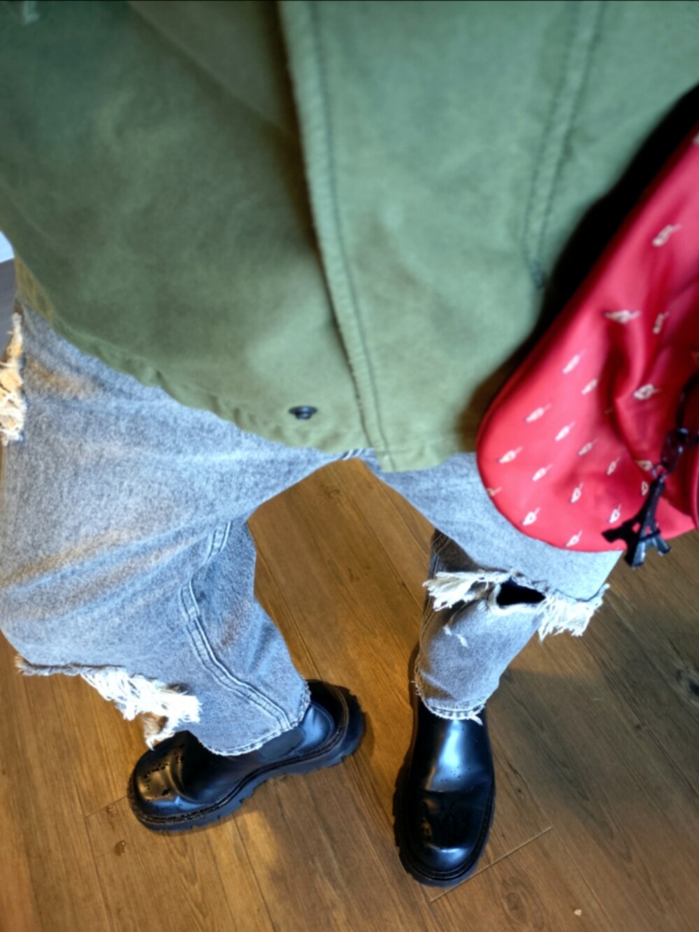 グリーン系のミリタリージャケット、レッド系のショルダーバッグ、グレー系のデニムパンツを着用したメンズの秋コーディネートの4枚目の写真