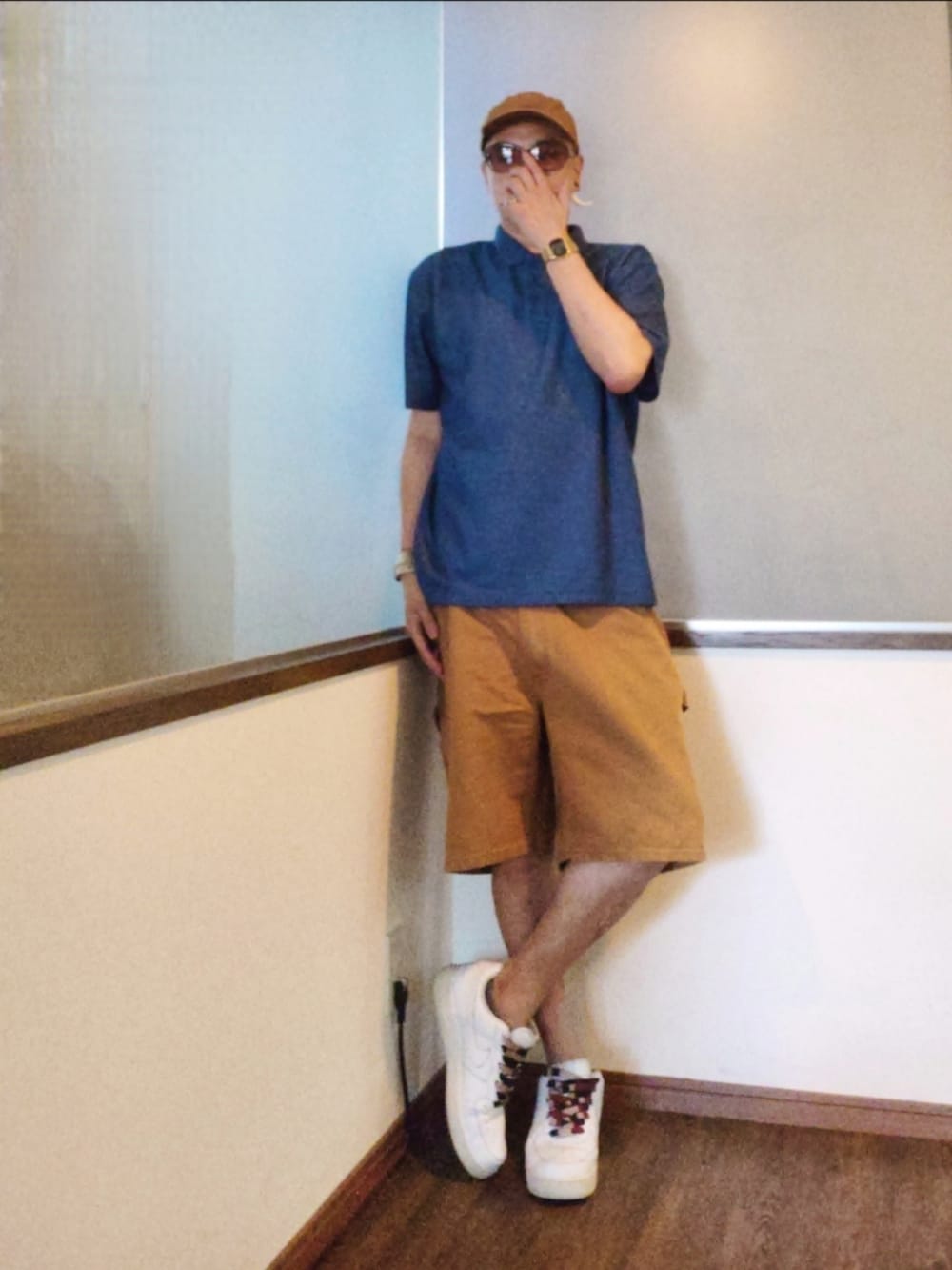 ブルー系のポロシャツ、ブラウン系のパンツ、ホワイト系のスニーカーを着用したメンズの夏コーディネートの2枚目の写真