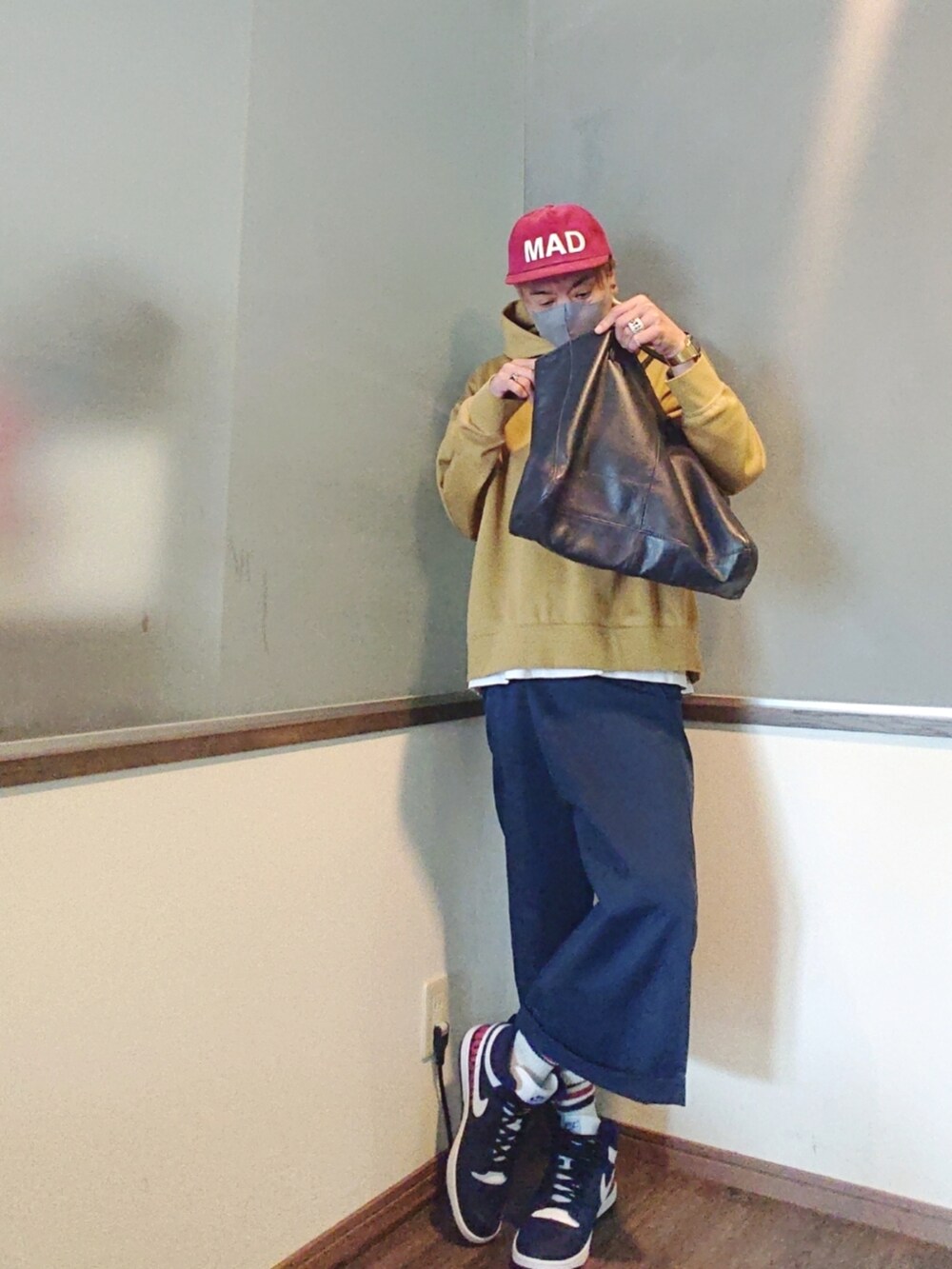 イエロー系のパーカー、ブルー系のチノパンツ、ブルー系のトートバッグを着用したメンズの夏コーディネートの2枚目の写真