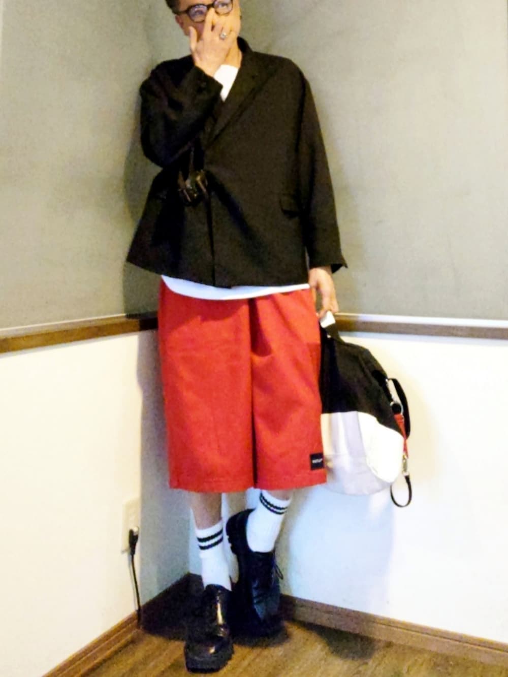 レッド系のチノパンツ、ホワイト系のショルダーバッグ、ブラック系のドレスシューズを着用したメンズの春コーディネートの2枚目の写真