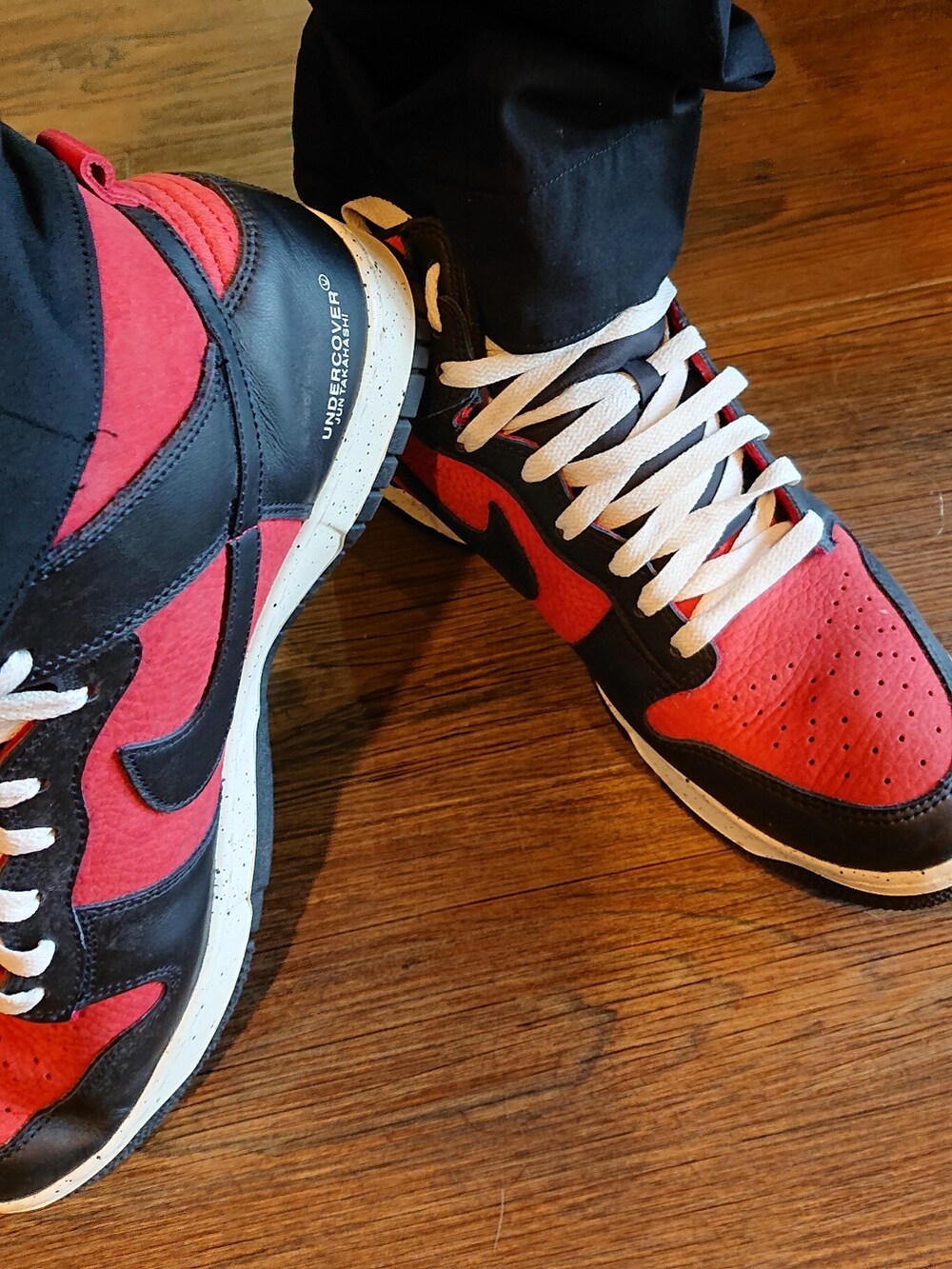 ブルー系のニット/セーター、ブラック系のスラックス、レッド系のスニーカーを着用したメンズの夏コーディネートの2枚目の写真