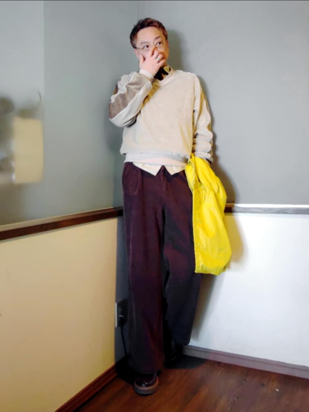 イエロー系のナイロンジャケット、ブラウン系のスラックス、ホワイト系のスウェットを着用したメンズの春コーディネートの2枚目の写真