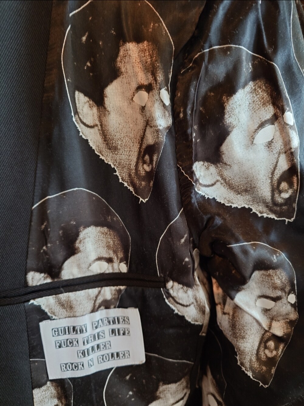 ブラック系のテーラードジャケット、ブラック系のニット/セーター、ブルー系のデニムパンツを着用したメンズの秋コーディネートの3枚目の写真