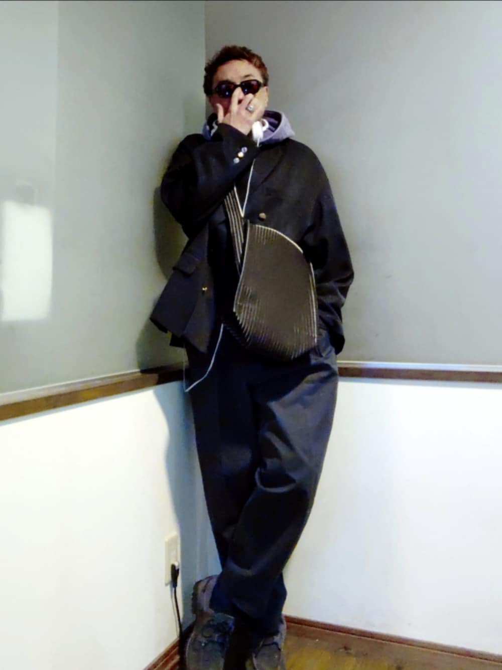 パープル系のパーカー、ブルー系のテーラードジャケット、ブラック系のショルダーバッグを着用したメンズの春コーディネートの2枚目の写真