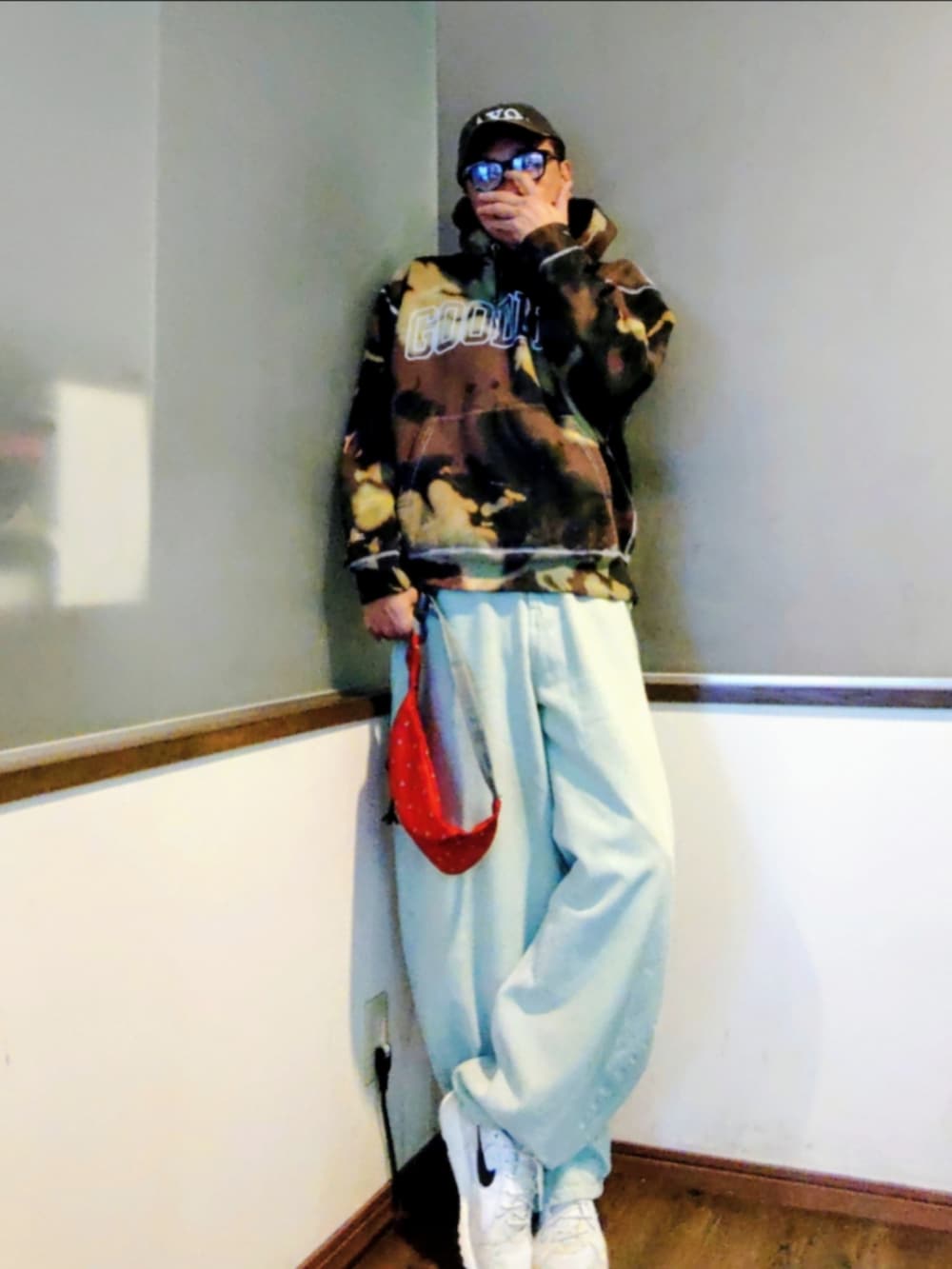 ブルー系のデニムパンツ、ブラック系のパーカー、レッド系のショルダーバッグを着用したメンズの秋コーディネートの4枚目の写真