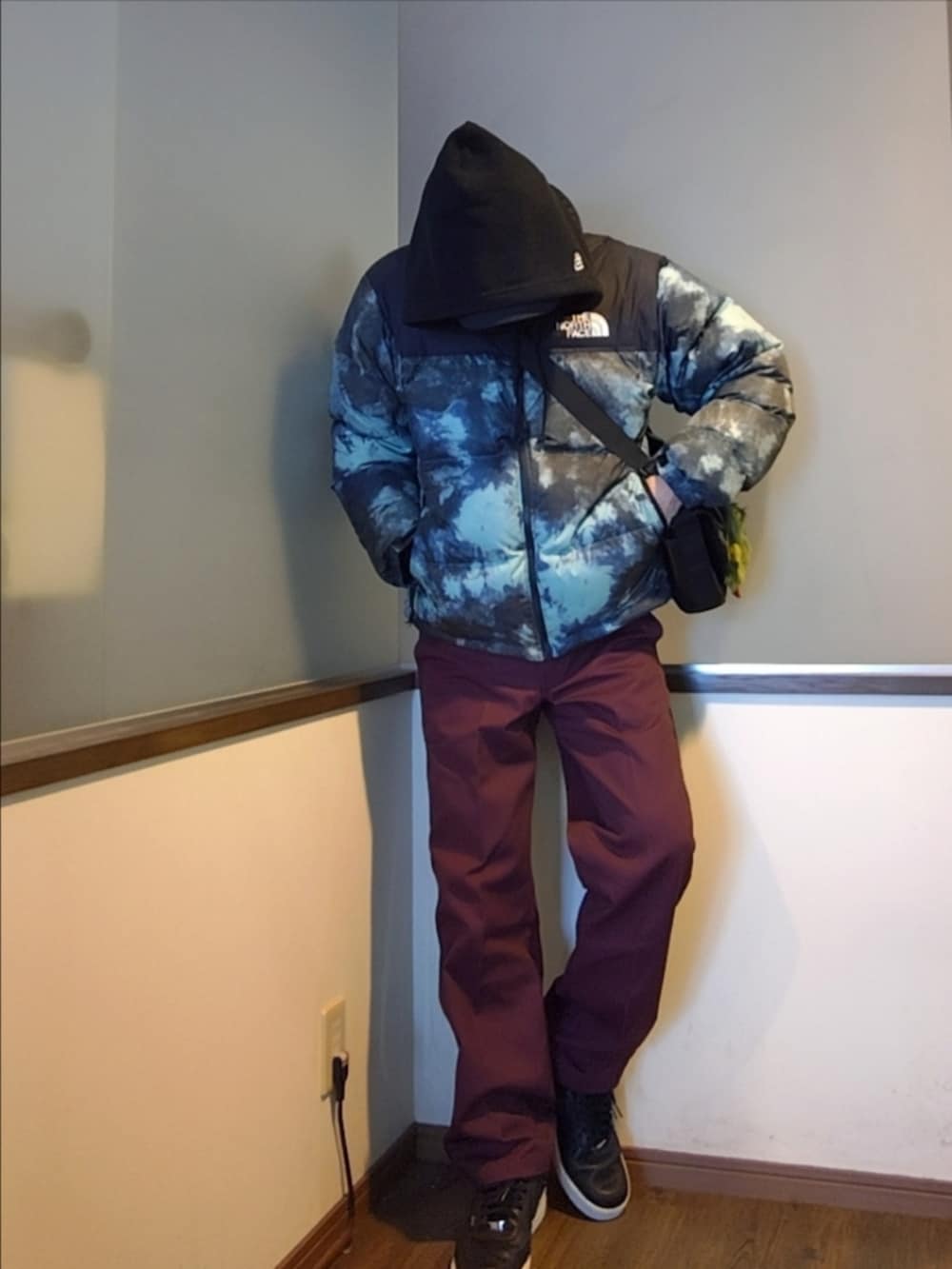 ブルー系のダウンジャケット/コート、ブラック系のニット/セーター、レッド系のチノパンツを着用したメンズの冬コーディネートの3枚目の写真