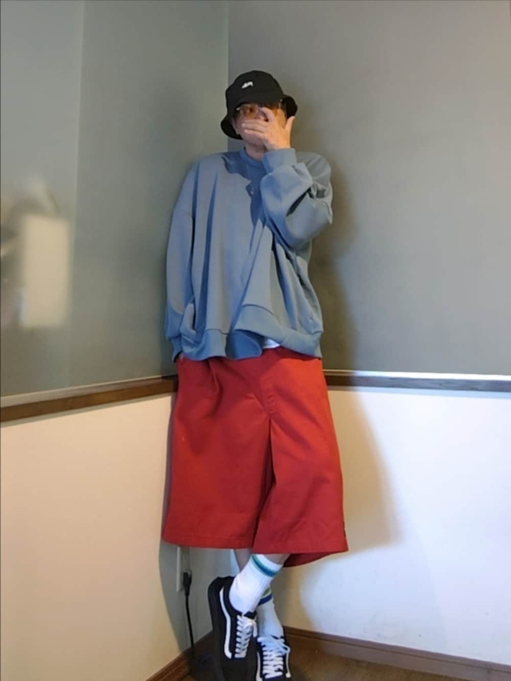 レッド系のチノパンツ、ブルー系のスウェット、ブラック系のスニーカーを着用したメンズの夏コーディネートの3枚目の写真