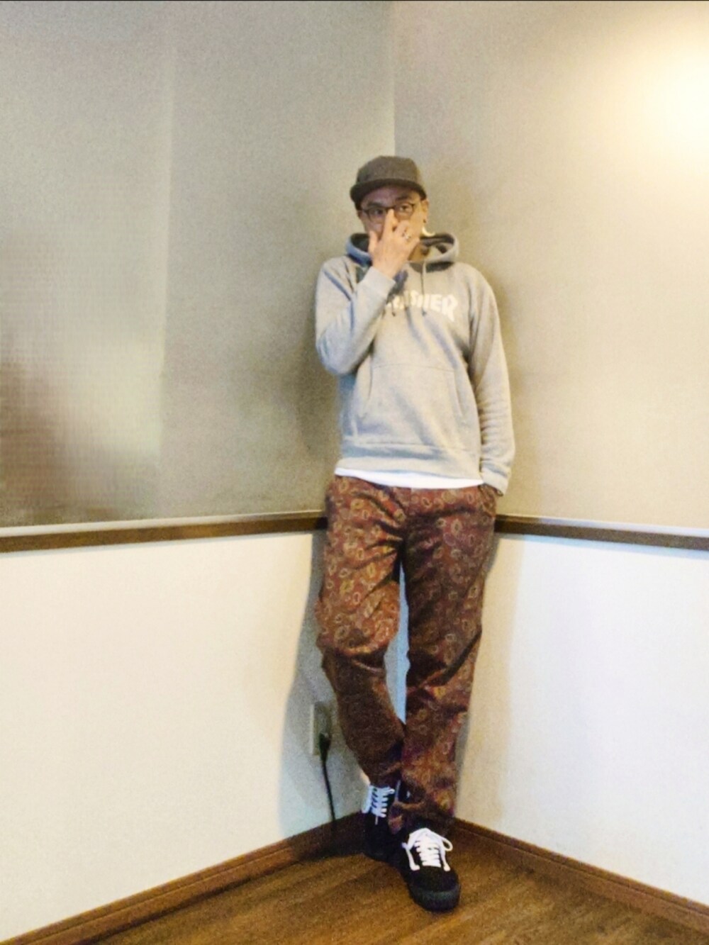 グレー系のパーカー、レッド系のチノパンツ、ブラック系のスニーカーを着用したメンズの秋コーディネートの2枚目の写真