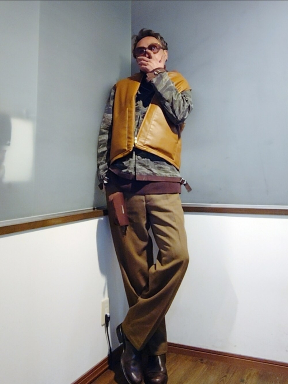 ブラウン系のダウンベスト、グリーン系のミリタリージャケット、ブラウン系のニット/セーターを着用したメンズの秋コーディネートの2枚目の写真