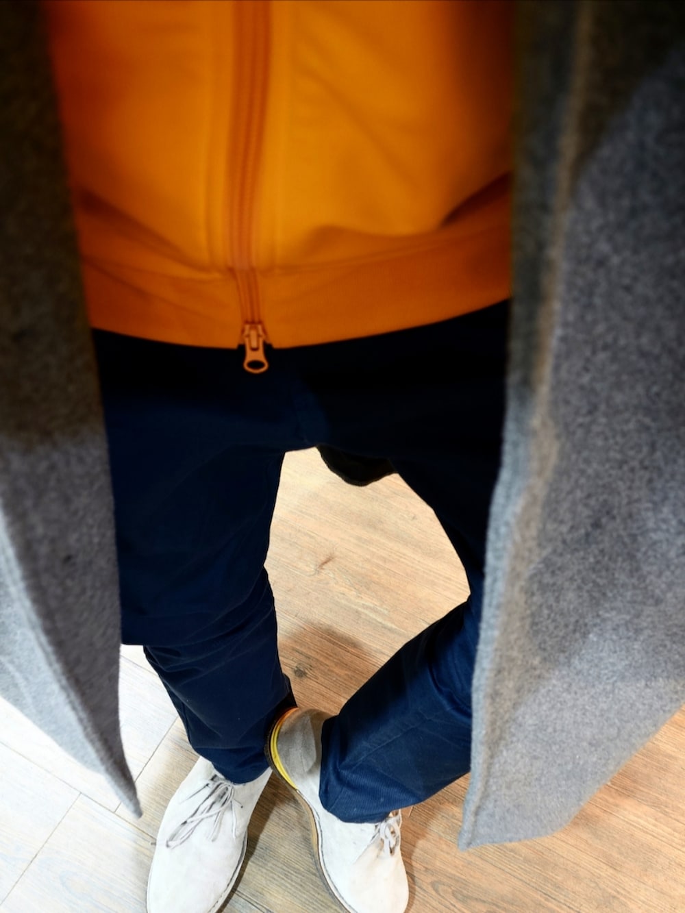 イエロー系のジャージ、グレー系のチェスターコート、ベージュ系のブーツを着用したメンズの秋コーディネートの2枚目の写真