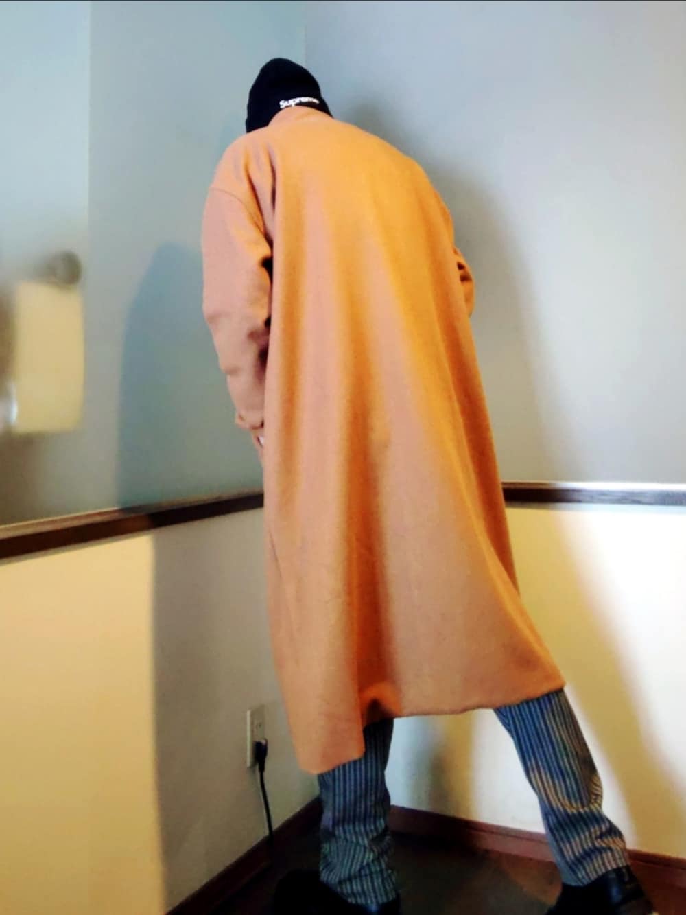 ブラック系のニット/セーター、ベージュ系のチェスターコート、グレー系のスラックスを着用したメンズの冬コーディネートの4枚目の写真