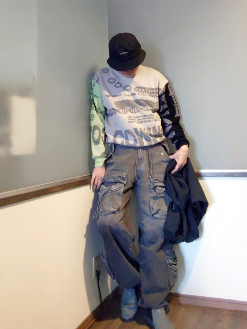 グレー系のニット/セーター、ブラック系のカーゴパンツ、グレー系のスニーカーを着用したメンズの春コーディネートの2枚目の写真