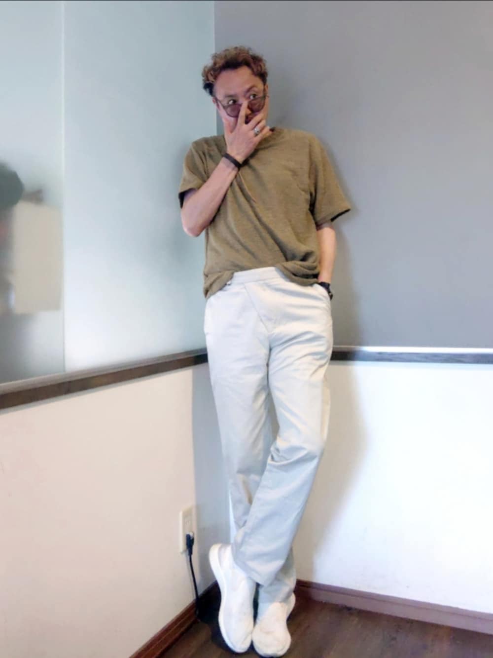 グリーン系のニット/セーター、ベージュ系のチノパンツ、ホワイト系のスニーカーを着用したメンズの夏コーディネートの2枚目の写真