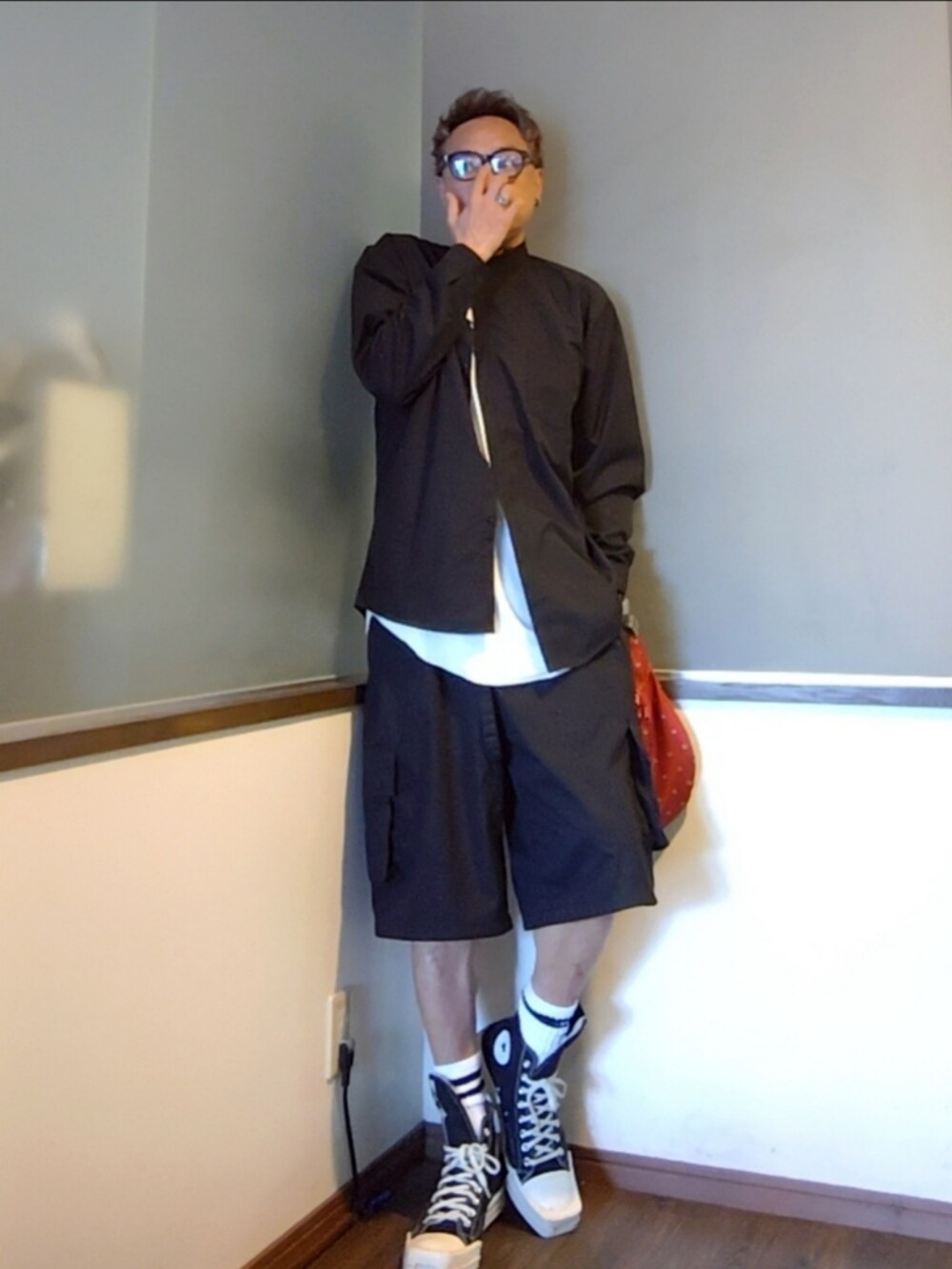 ブラック系のスニーカー、レッド系のショルダーバッグ、ブラック系のカーゴパンツを着用したメンズの夏コーディネートの2枚目の写真