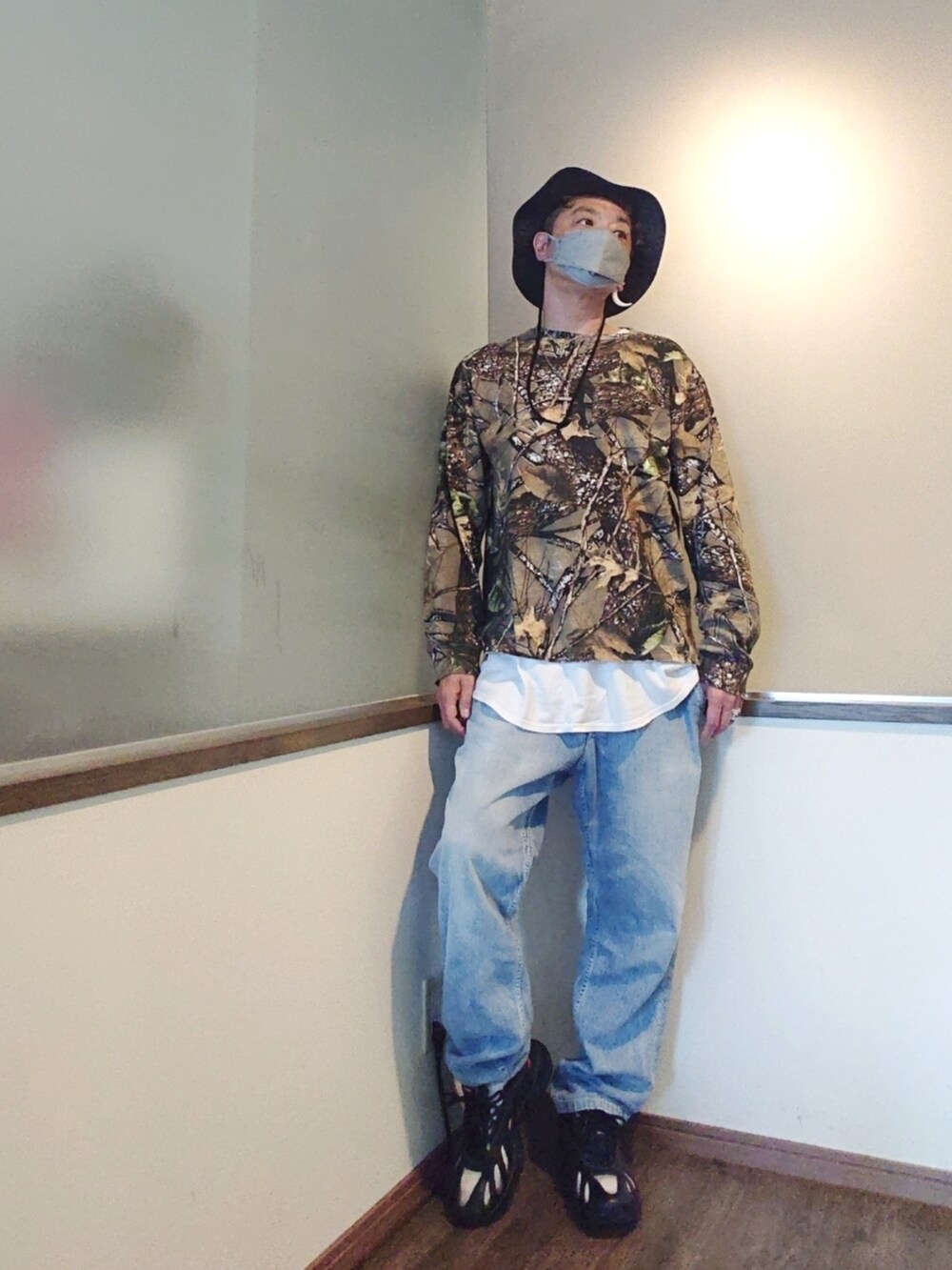 ベージュ系のTシャツ/カットソー、ブルー系のデニムパンツ、ブラック系のスニーカーを着用したメンズの夏コーディネートの2枚目の写真