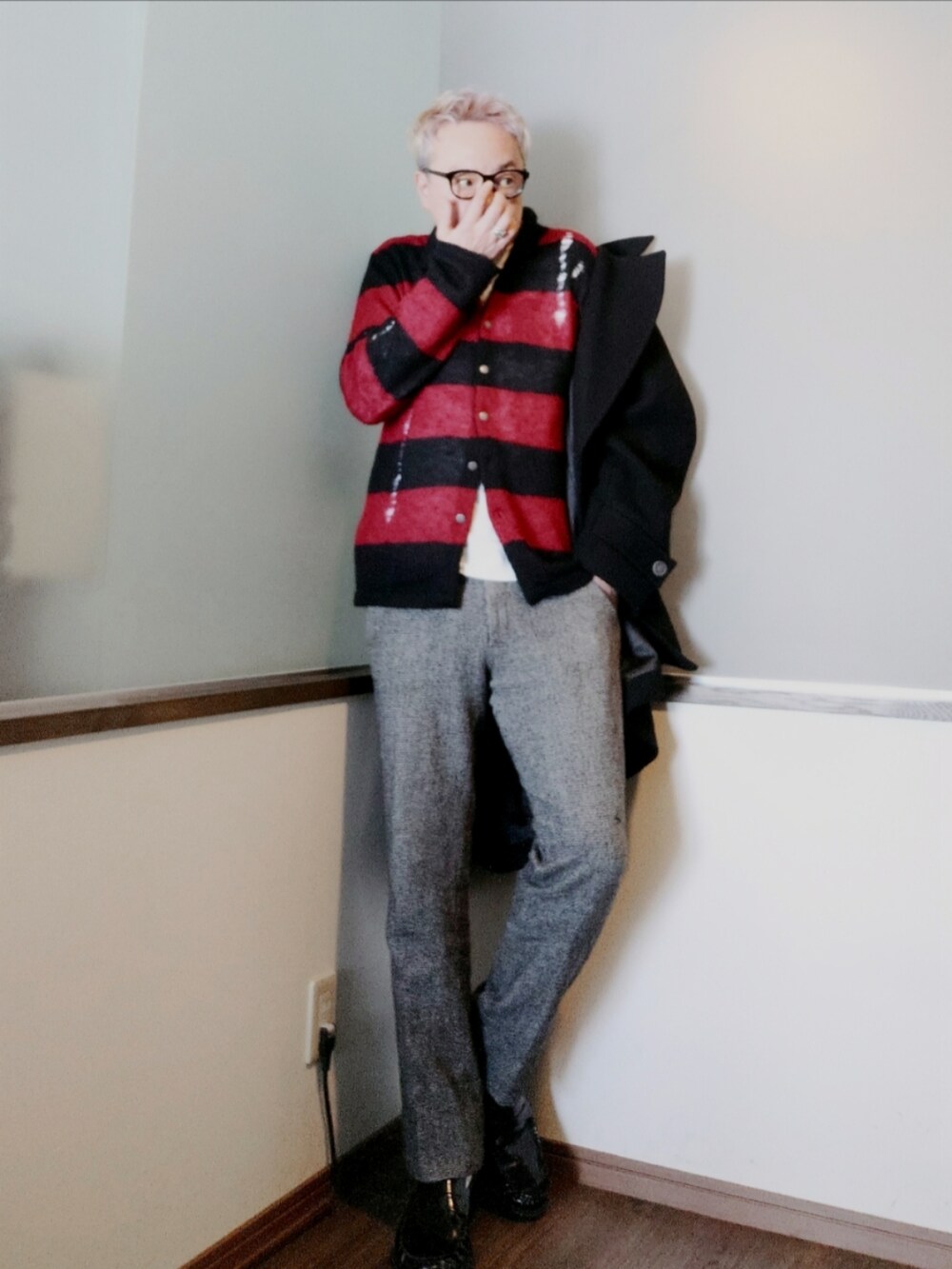 ブラック系のピーコート、レッド系のカーディガン/ボレロ、ブラック系のスラックスを着用したメンズの冬コーディネートの2枚目の写真