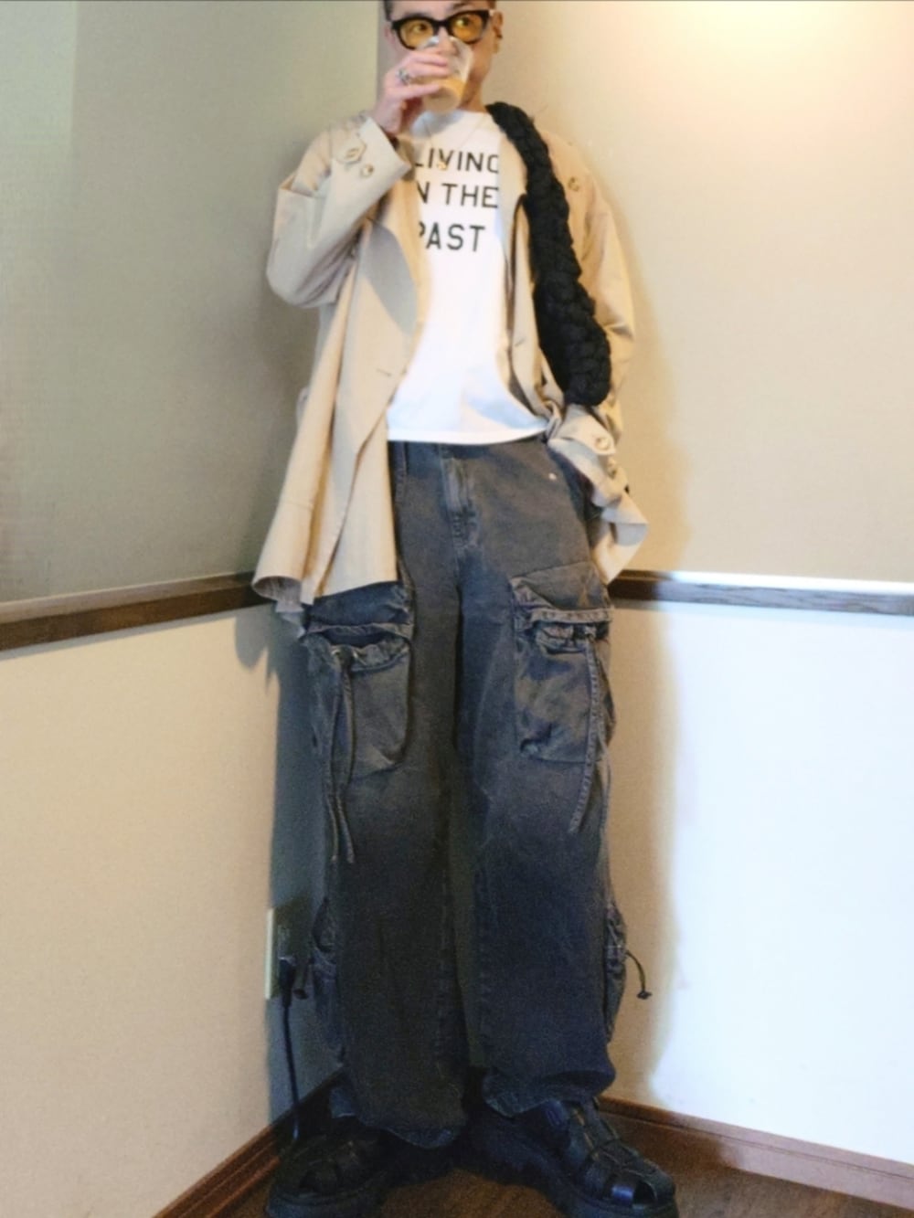 ベージュ系のトレンチコート、ホワイト系のTシャツ/カットソー、ブラック系のカーゴパンツを着用したメンズの夏コーディネートの2枚目の写真
