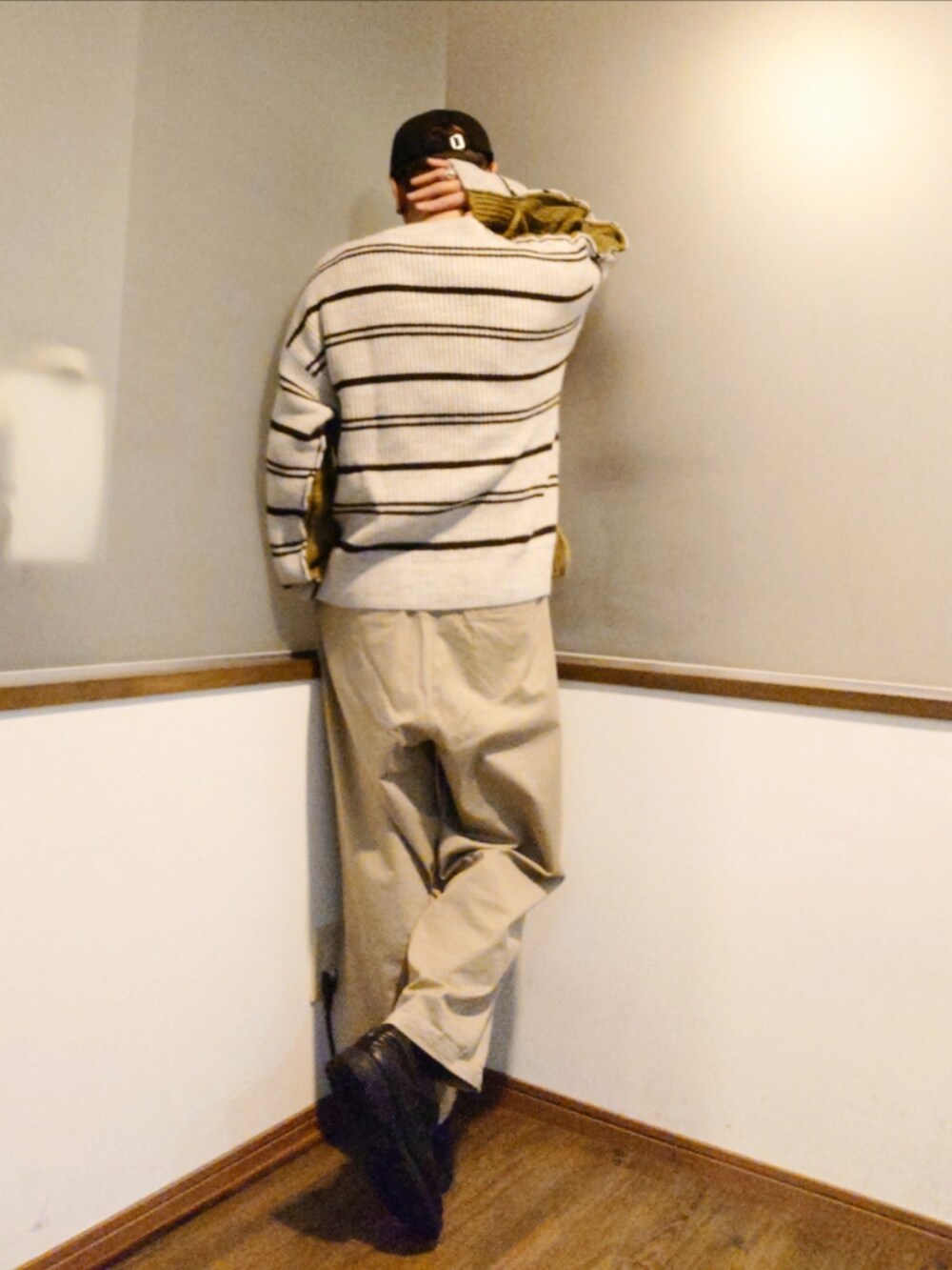 グリーン系のニット/セーター、ブラック系のピーコート、ベージュ系のチノパンツを着用したメンズの冬コーディネートの5枚目の写真