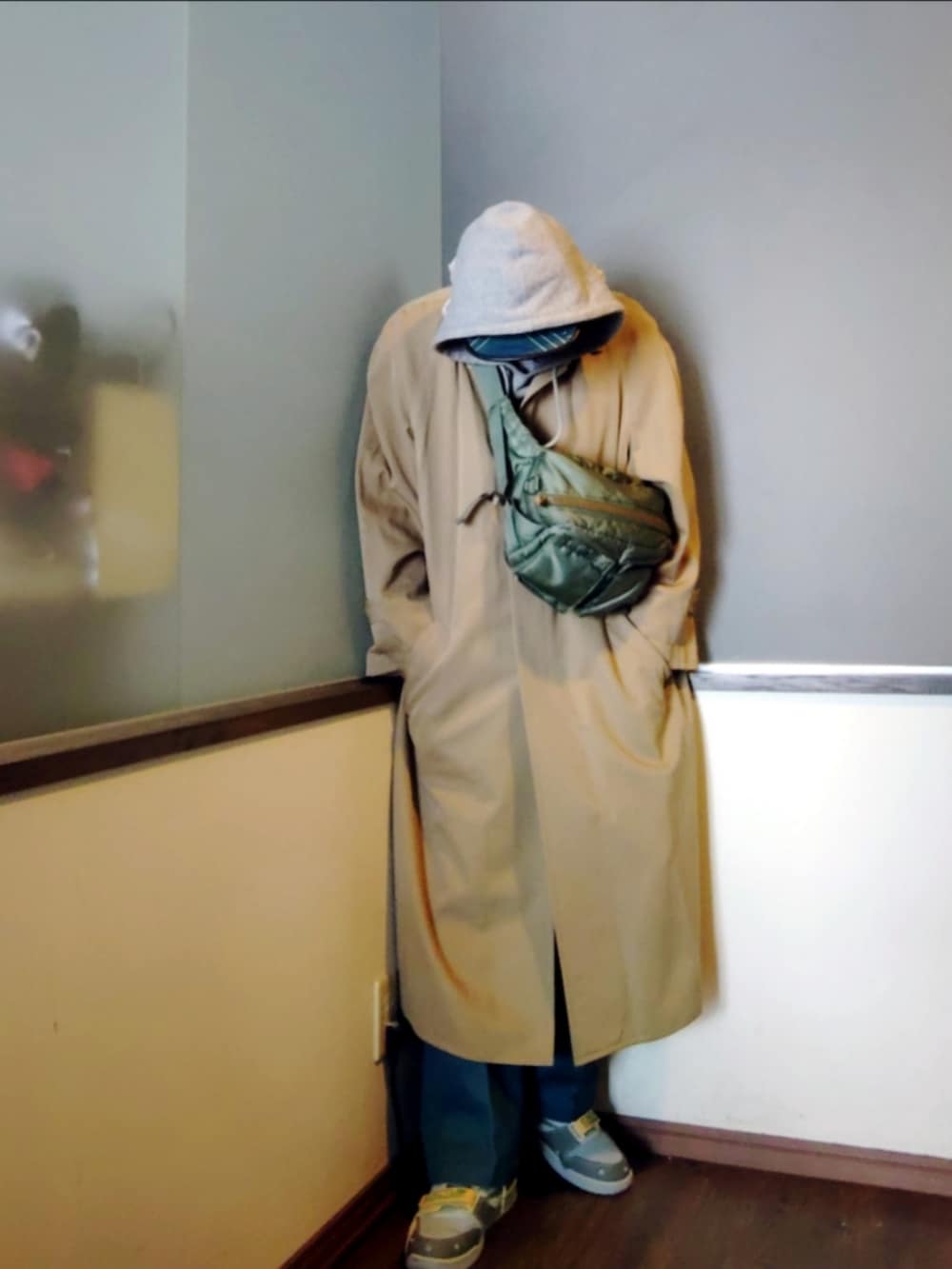 ベージュ系のトレンチコート、グリーン系のボディバッグ/ウエストポーチ、グリーン系のチノパンツを着用したメンズの春コーディネートの3枚目の写真