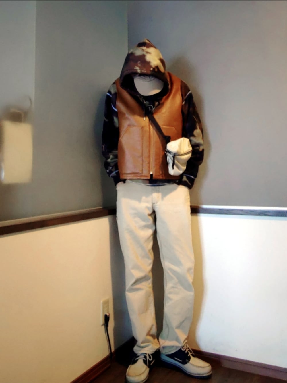 ブラウン系のダウンベスト、ブラック系のパーカー、ブラウン系のパンツを着用したメンズの春コーディネートの3枚目の写真