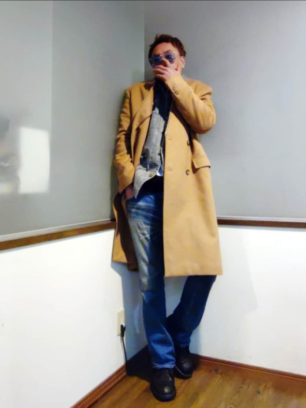 ブルー系のカバーオール、ブラック系のニット/セーター、ベージュ系のチェスターコートを着用したメンズの冬コーディネートの2枚目の写真