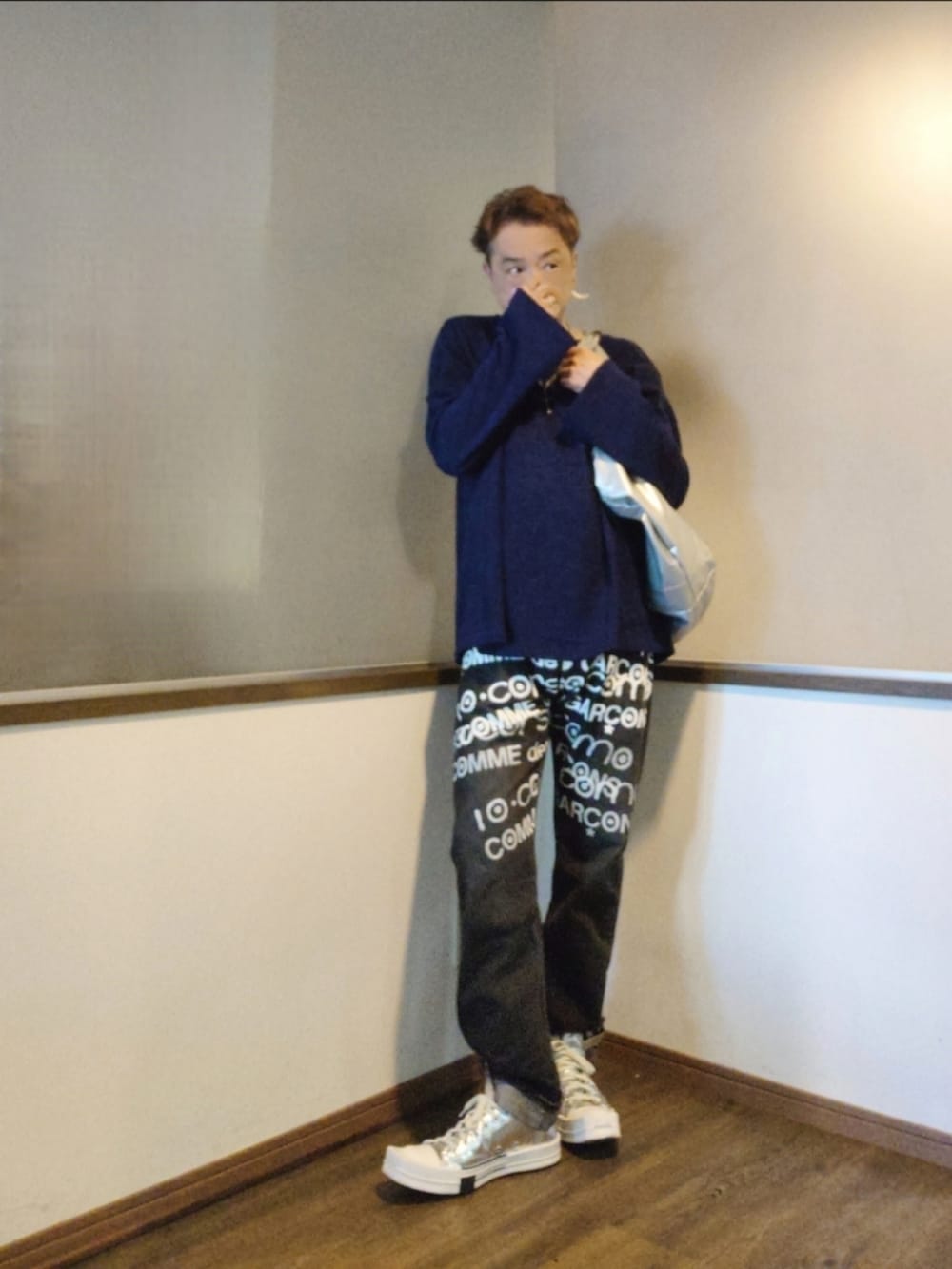 ブルー系のニット/セーター、シルバー系のトートバッグ、ブラック系のデニムパンツを着用したメンズの秋コーディネートの2枚目の写真