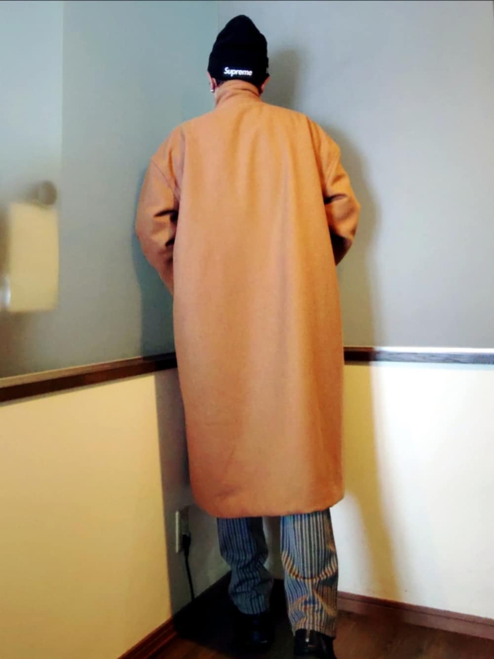 ブラック系のニット/セーター、ベージュ系のチェスターコート、グレー系のスラックスを着用したメンズの冬コーディネートの3枚目の写真