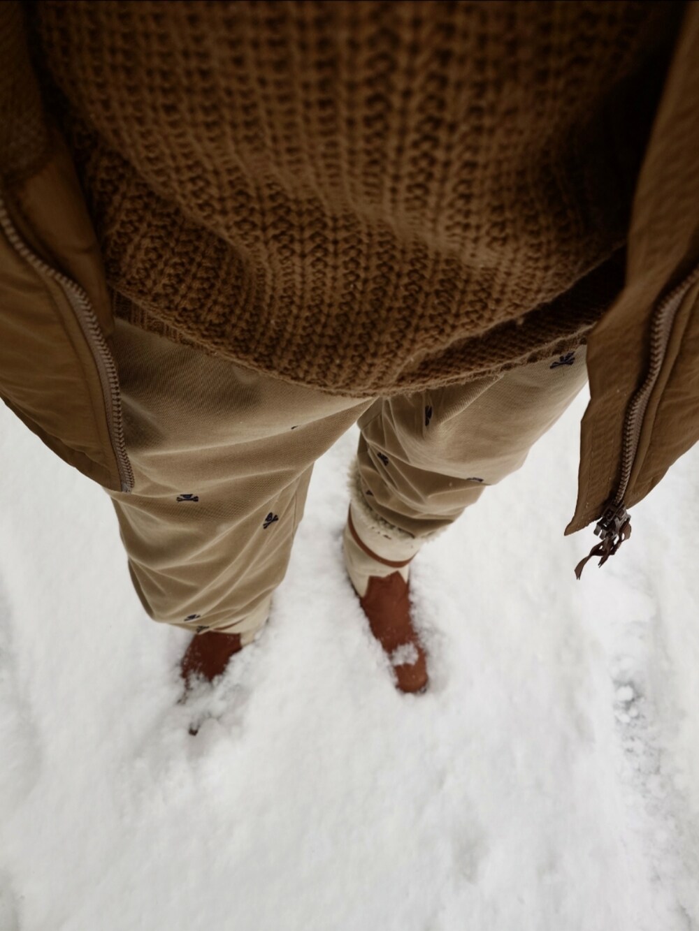 ベージュ系のダウンジャケット/コート、ベージュ系のニット/セーター、ベージュ系のチノパンツを着用したメンズの秋コーディネートの2枚目の写真