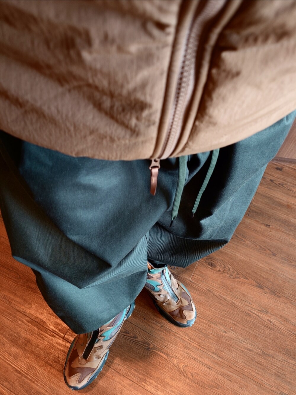 ベージュ系のダウンジャケット/コート、グリーン系のブルゾン、グリーン系のパンツを着用したメンズの秋コーディネートの5枚目の写真