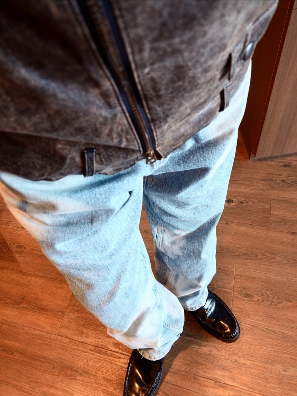 ブラウン系のライダースジャケット、ブルー系のデニムパンツ、ブラック系のローファーを着用したメンズの冬コーディネートの2枚目の写真