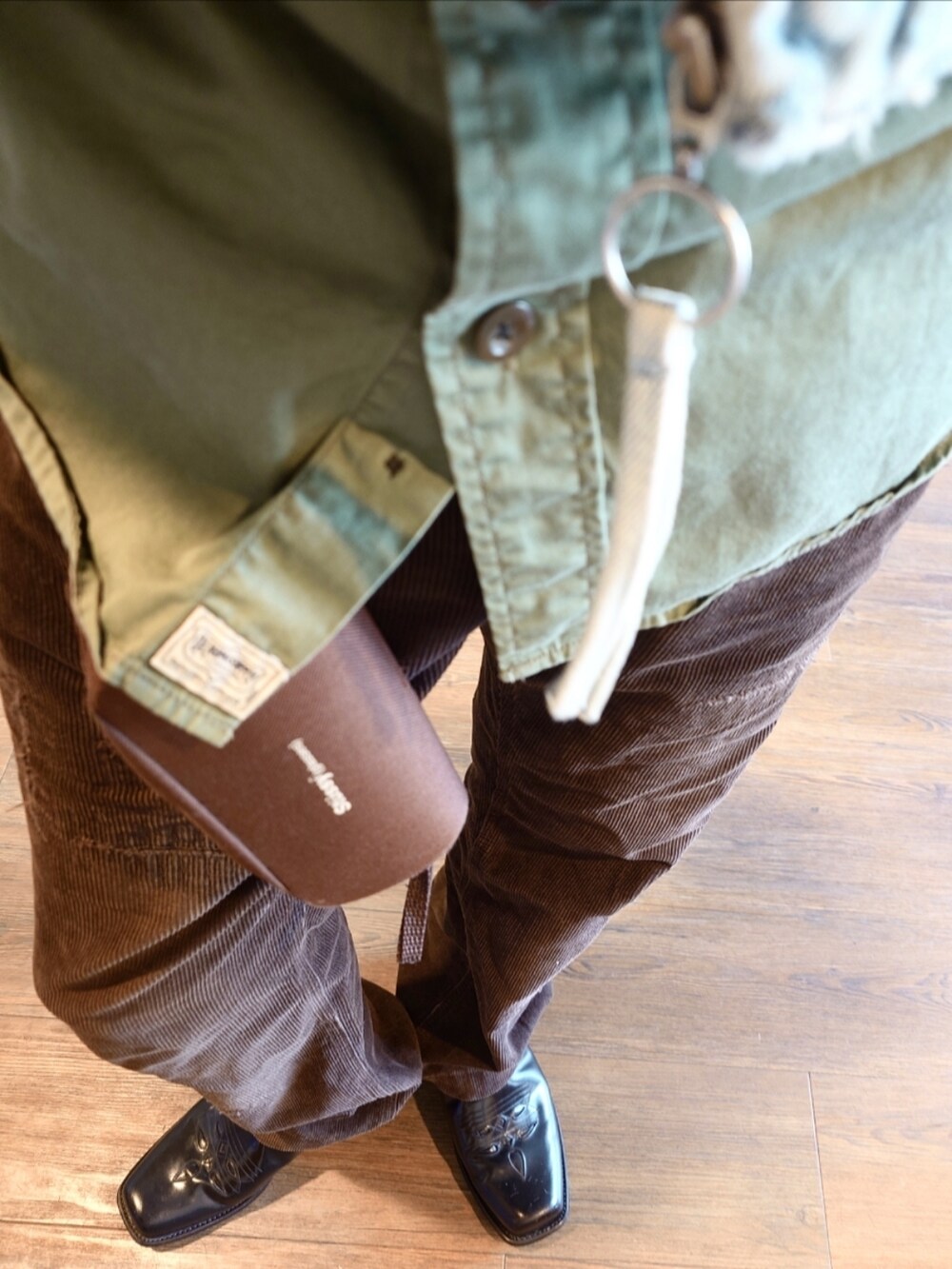 ブラウン系のパンツ、ブラック系のブーツ、グリーン系のシャツ/ブラウスを着用したメンズの秋コーディネートの3枚目の写真