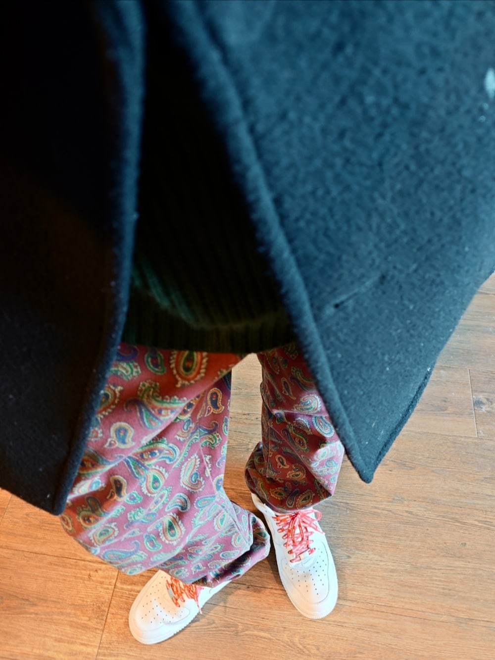 ブラック系のピーコート、レッド系のチノパンツ、ホワイト系のスニーカーを着用したメンズの冬コーディネートの3枚目の写真