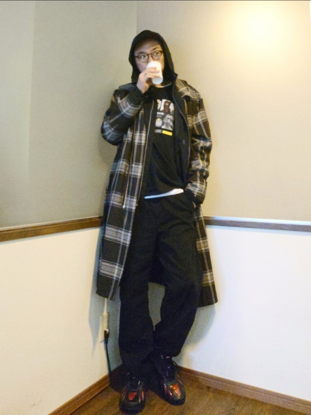 ブラック系のナイロンジャケット、ブラック系のステンカラーコート、ブラック系のチノパンツを着用したメンズの春コーディネートの2枚目の写真